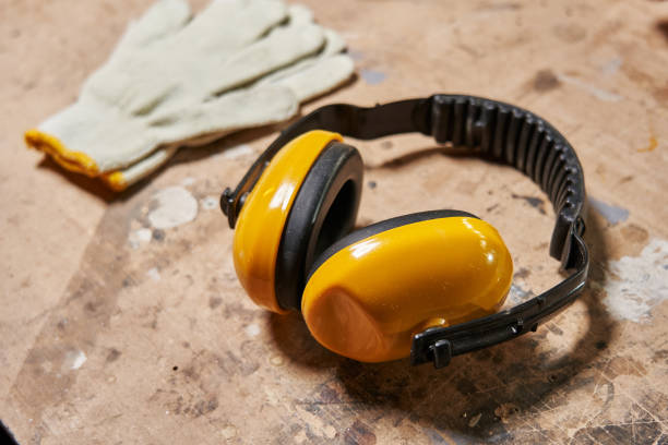 yellow earmuffs and white protective cotton gloves lie on a wooden workbench. High quality photo