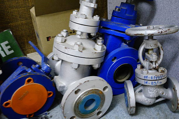 A close-up of various valves, flanges, and pipe fittings, suggesting a workshop or storage area for industrial plumbing supplies.